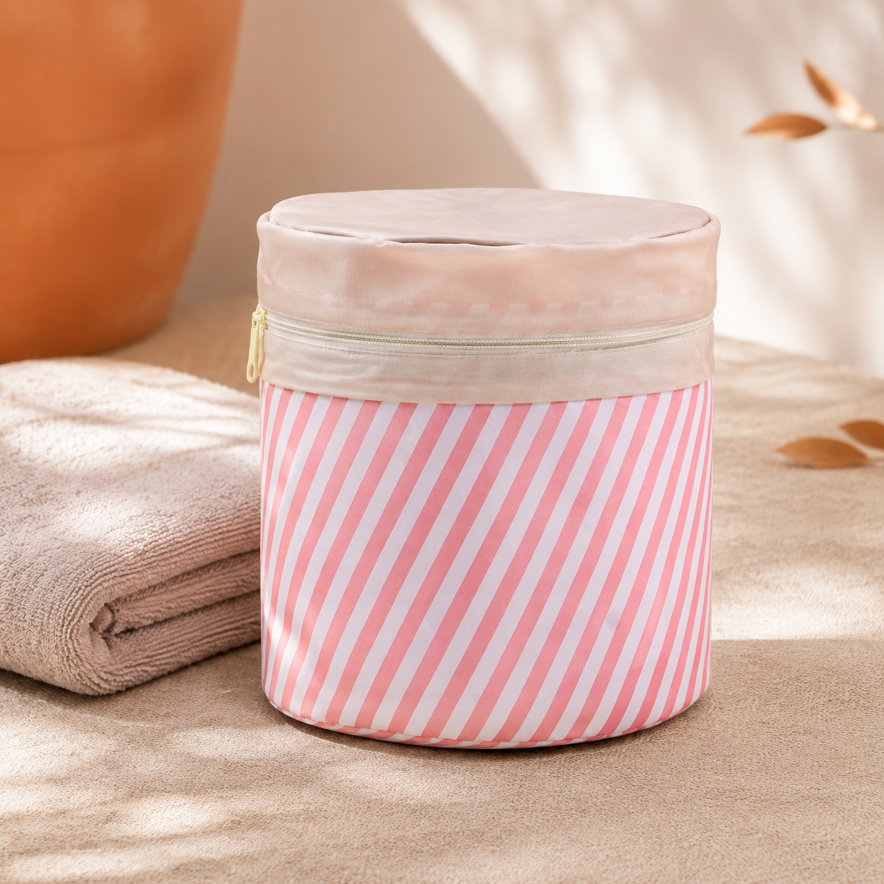 Pink-and-white striped round cosmetic bag on warm linen