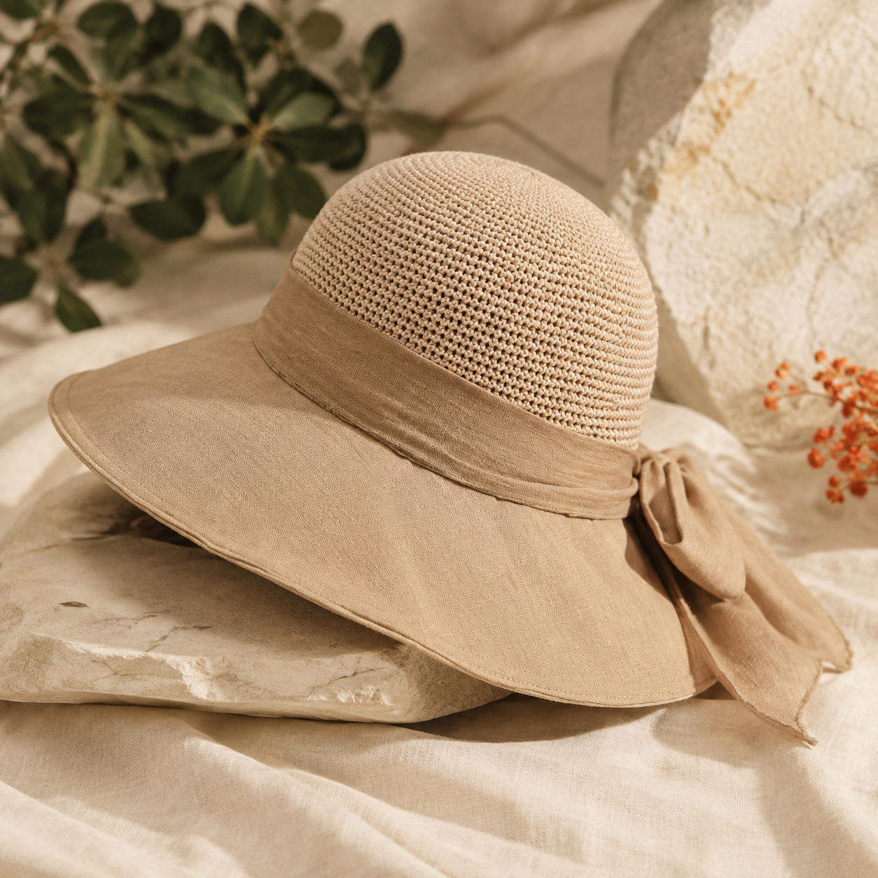 Tan knitted wide-brim sun hat on warm ivory linen